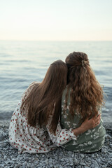 Girlfriends sitting with their backs on the sea