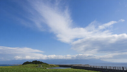 澄み切ったさわやかな日本の冬の青空と長く伸びた雲　海岸や湖の岸に山々の影　正月・新年・アウトドア　朝のイメージ　