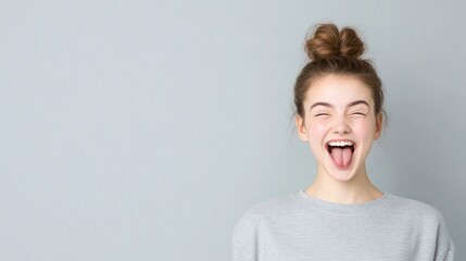 Happy young woman making a playful face against a gray background.