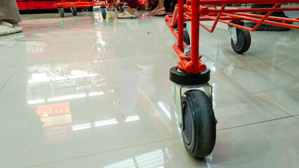 low angle of a shopping trolley wheel with a white floor in a supermarket