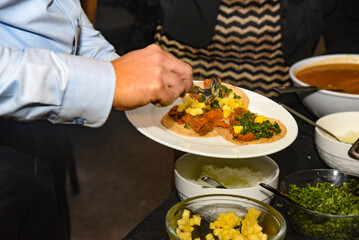 A man is serving food on a plate, including tacos and rice