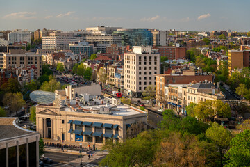 Fototapeta premium A scenic view of a vibrant urban landscape with historic architecture, tree-lined streets, and modern buildings is seen in a city center during sunset.