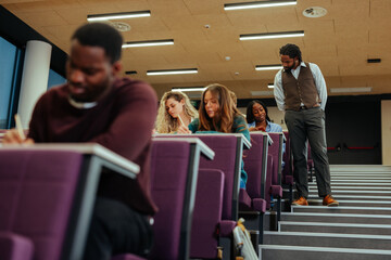 Professor supervising students taking exam in university lecture hall