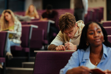 University student taking notes during lecture in auditorium