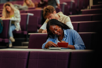 Focused university student taking notes during lecture in auditorium