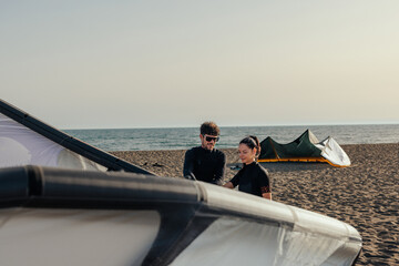 Two people setting up a kite for kitesurfing on a beach