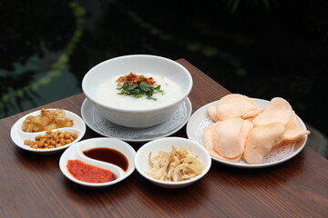 indonesian food chicken poridge on white bowl with cracker on wooden table