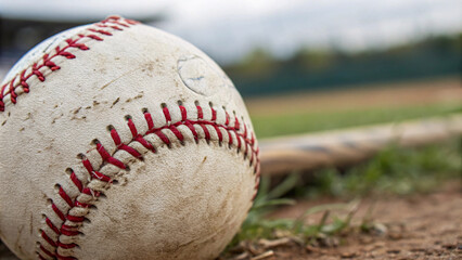 Detailed view of a weathered baseball nestled in the grass, evoking nostalgia for moments spent on the diamond