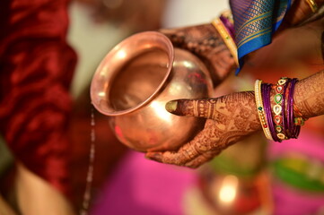 drops water and petals on brides and grooms hands. Water jug. Bride and groom holding hands of each other. Kanyadaan ceremony. Marathi Wedding Rituals. Maharashtra. Henna hands