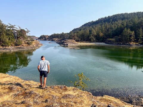 A man admiring a beautiful view of a cove on a beautiful summer day surrounded by forest and ocean on Jedediah Island Marine Park