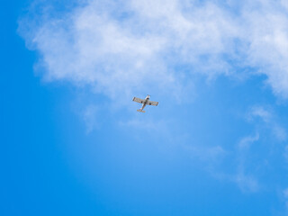 Small ultralight airplane with overhead wing and single propeller flying in sunset sky.