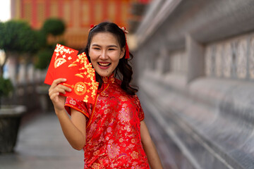 Smiling Woman in Red Qipao Holding a fan Red Envelope in Traditional temple