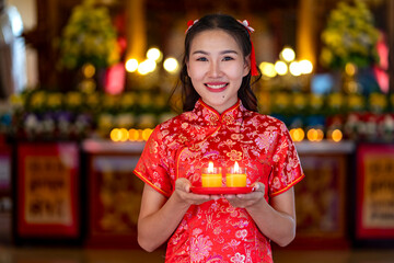 Young beautiful Woman in red dress with candle Praying During Chinese New Year