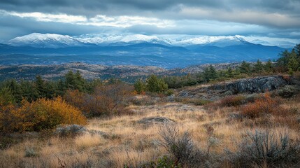 A serene mountain landscape with snow-capped peaks and autumn foliage.