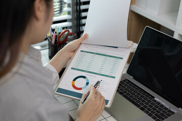 A woman is pointing at a graph on a piece of paper. The graph shows a comparison between two sets of data. The woman is using a pen to highlight the differences between the two sets of data