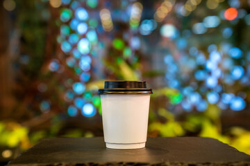empty wooden table top disposable cup for coffee or tea in cafe. Hot coffee in white paper cup isolated on wood table background. Blank paper cup of coffee in a coffee shop for the application logo. 