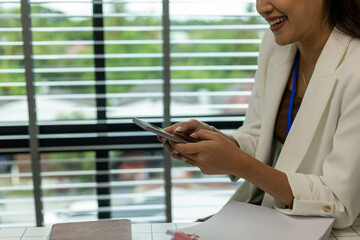 A woman is sitting at a desk with a tablet in her hand. She is smiling and she is enjoying herself