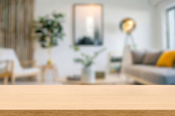 empty wooden table top blurred view of modern living room with sofa and soft bench. room interior with couch, armchair and coffee table or shelving units. stylish living room. comfortable workplace.