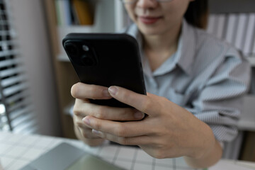 A woman is sitting at a desk with a tablet in her hand. She is smiling and she is enjoying herself