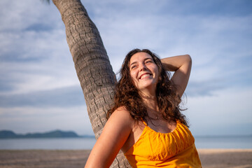 Portrait beautiful woman against a palm tree on a serene beach relaxed and confident, enjoying the peacefulness of the environment leisure and the beauty of nature concept.