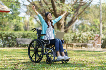 Obraz premium Young asian woman in wheelchair working with laptop