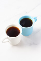 
淹れたてのコーヒーが入ったふたつのマグカップで、ふたりがコーヒーを飲みながら、打ち合わせをしているイメージ
