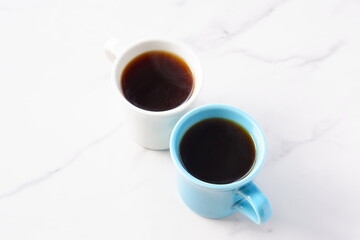 
淹れたてのコーヒーが入ったふたつのマグカップで、ふたりがコーヒーを飲みながら、打ち合わせをしているイメージ
