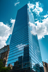 Modern Skyscraper with Sleek Glass Facade Reflecting Cityscape Under Bright Blue Sky - Contemporary Urban Architecture