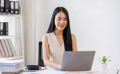 Businessasian woman using laptop computer in office. Happy young woman, entrepreneur, small business owner working online.
