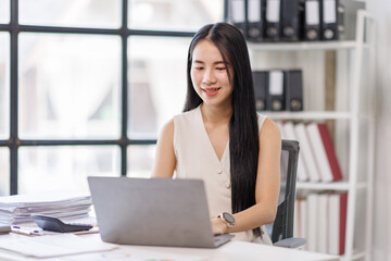 Businessasian woman using laptop computer in office. Happy young woman, entrepreneur, small business owner working online.
