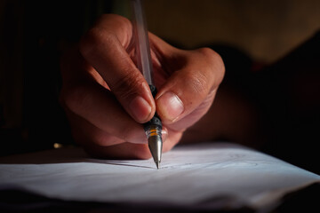 Close-up of a man's hand writing on paper at night, hand writing a letter, writing in a diary