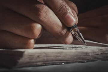 Close-up of a man's hand writing on paper at night, hand writing a letter, writing in a diary