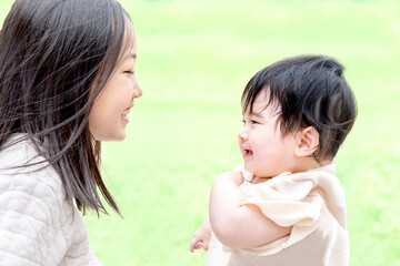 新緑の公園で姉と遊ぶ赤ちゃん。家族、愛情、仲良しイメージ