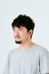 Fototapeta premium 白背景で右側を向いた30代の1人の髭を生やした日本人男性の人物の上半身