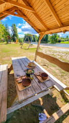 Idyllic picnic at a covered picnic bench at a children's playground by a small river with trees in summer in Estonia