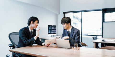 オフィスでミーティングをする20代から30代の若手の社員2人