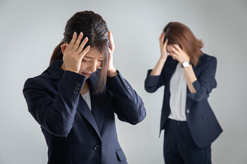 頭を抱えるスーツの女性