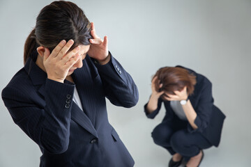 頭を抱えるスーツの女性