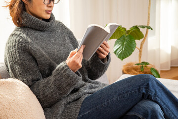 ソファーに座って読書をするミドル女性