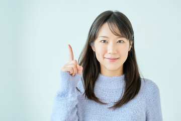 人差し指を上げるポーズをする若い女性