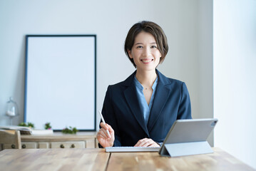 タブレットPCの前に座るスーツ姿の女性