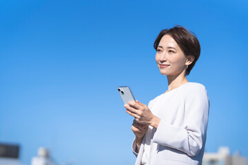 青空の下にいる日本人ビジネスウーマン