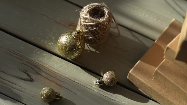 Holiday decor. Packing holiday gifts. Gift boxes, natural twine and Christmas gold balls on a wooden background.