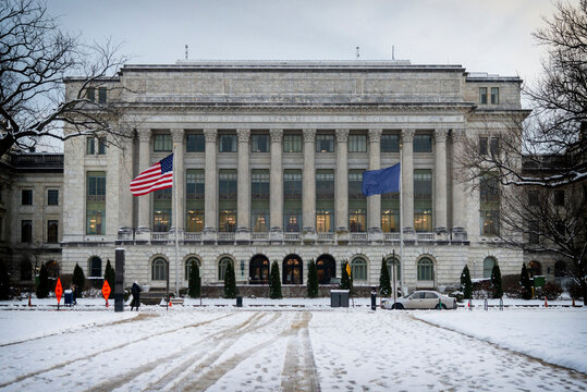 Close-up view of the USDA building in winter with snow-covered grounds, American and department flags, and historic architecture in Washington, D.C.