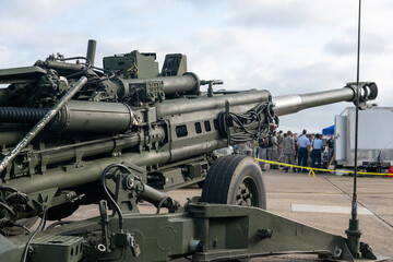 Close-up of a military field artillery cannon on display at an outdoor event, with people in...