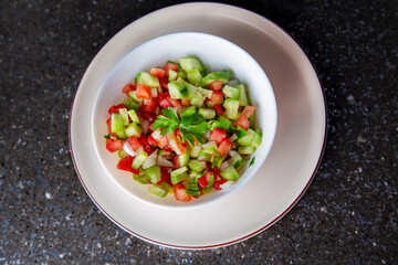 Fresh salad with cucumber, tomato, onion, parsley and olive oil close-up top view