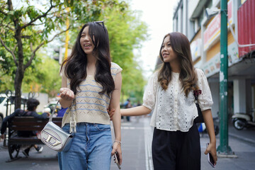 happy two asian women walking on the street