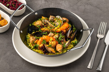 Top view of traditional Spanish seafood paella with rice, mussels and shrimps in a pan on wooden table