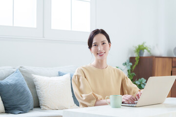 家でパソコンを使って仕事する女性
