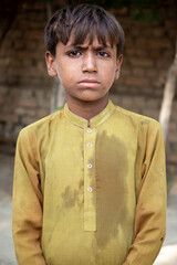 Candid Portrait of a Young Boy in Yellow Traditional Clothing with a Thoughtful Expression Outdoors